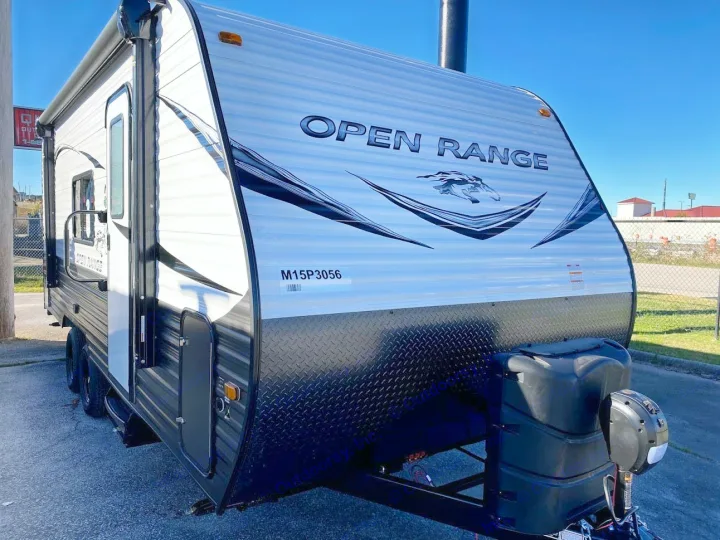 An eye-level view of a new "OPEN RANGE" travel trailer, a great rv rental choice, parked outside on a sunny day.. Open Range 20MB 2021
