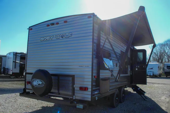 Grey Wolf travel trailer for rv rental, showing rear & side with extended awning, steps, & spare tire.. Forest River Cherokee Grey Wolf 2021