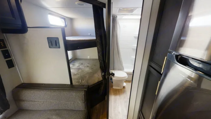 RV rental interior showing bunk beds, a compact bathroom with shower & toilet, and a refrigerator.. Forest River Cherokee Grey Wolf 2021
