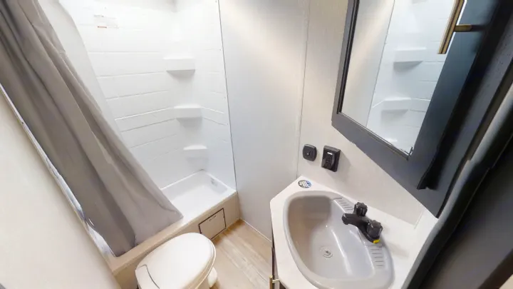 This RV rental bathroom features a compact shower, toilet, and corner sink, offering comfort on your adventures.. Forest River Cherokee Grey Wolf 2021