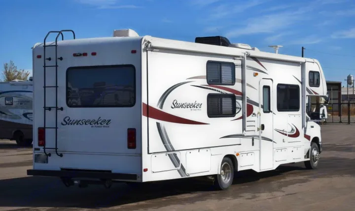 White Sunseeker RV rental, a Class C motorhome, with an exterior ladder and distinctive side graphics.. Forest River Sunseeker 2015