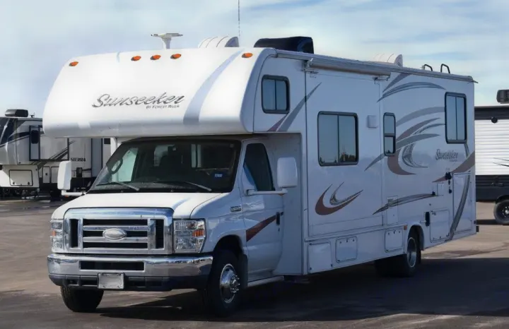 A white Sunseeker Class C RV, ideal for rv rental. This motorhome features a cab-over bunk and decorative side decals.. Forest River Sunseeker 2015