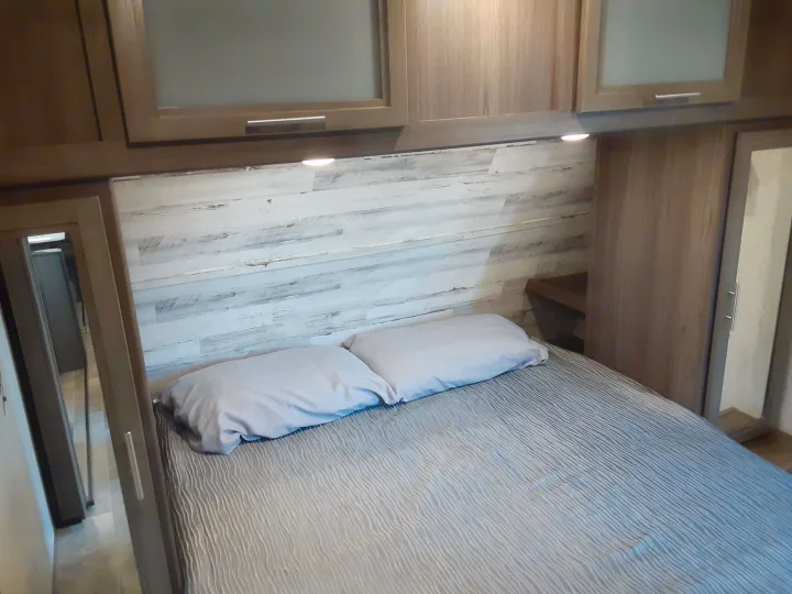 RV rental: Modern bedroom featuring a comfortable bed, overhead cabinets, under-cabinet lighting, and mirrored closet.. Dutchmen Kodiak 2020