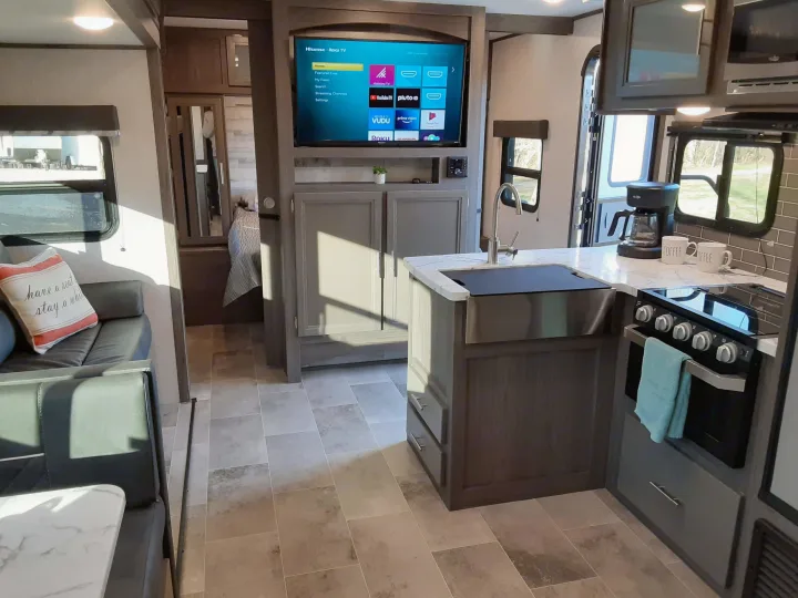 Modern rv rental interior: kitchen island, coffee maker, smart TV, and a comfortable sofa/dinette area.. Dutchmen Kodiak 2020