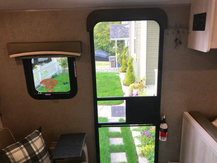 RV rental interior view: window with outdoor scene, screen door, key hooks, monitor panel, and fire extinguisher.. Forest River Rockwood 2021