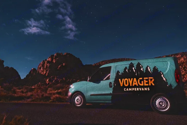 A Voyager campervan RV rental is parked by desert mountains under a starry night sky, ready for adventure.. Dodge Promaster City 2019