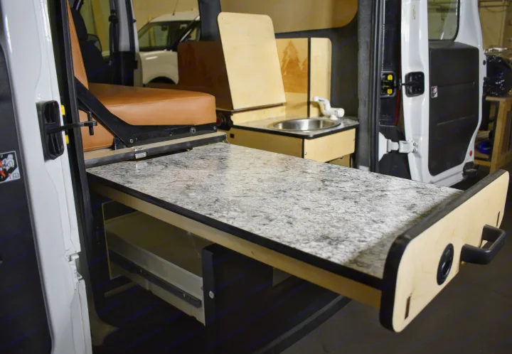 This RV rental features a pull-out counter and kitchenette, optimizing space in a modern camper van interior.. Dodge Promaster City 2019