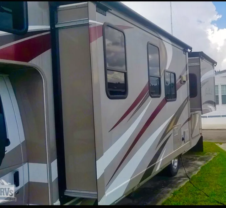 Side view of a modern RV rental motorhome with extended slide-out, parked for your next camping adventure.. Other Four Winds 2016