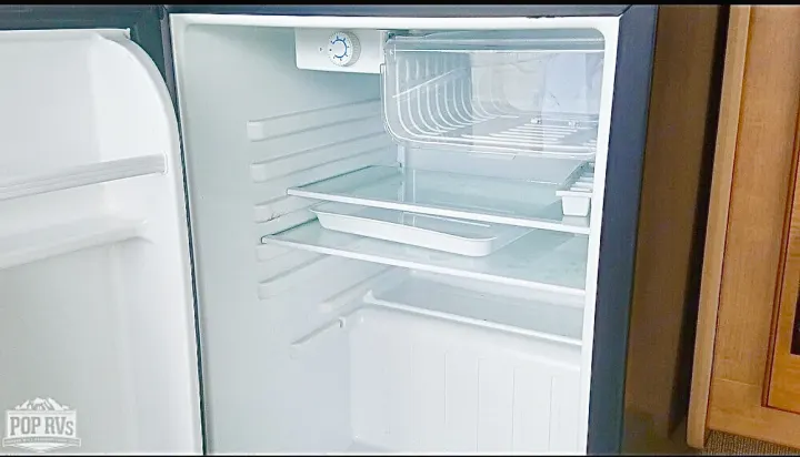 RV rental's clean, empty mini-fridge with glass shelves, top freezer. Essential compact kitchen storage for travel.. Other Four Winds 2016