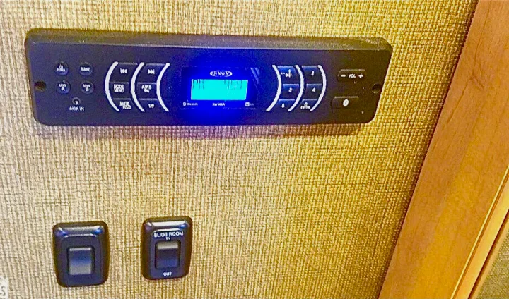 RV rental interior: A Jensen stereo receiver displaying 'PM 4:59', with unlabeled and slide room controls below.. Other Four Winds 2016