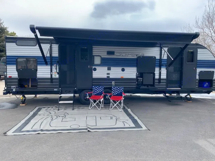 Explore the open road with this Grey Wolf RV rental, complete with an extended awning and cozy outdoor setup.. Cherokee Grey Wolf 27DBH 2021