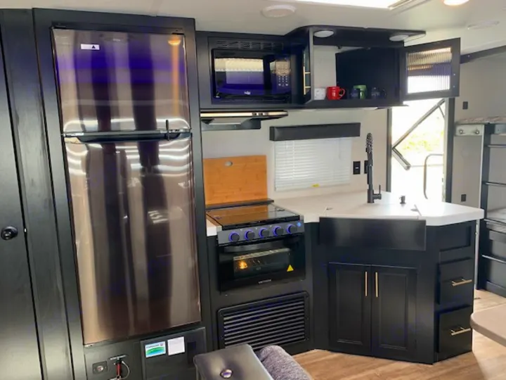 Step inside this RV rental's modern kitchen featuring a fridge, stove/oven, microwave, and deep sink.. Cherokee Grey Wolf 27DBH 2021