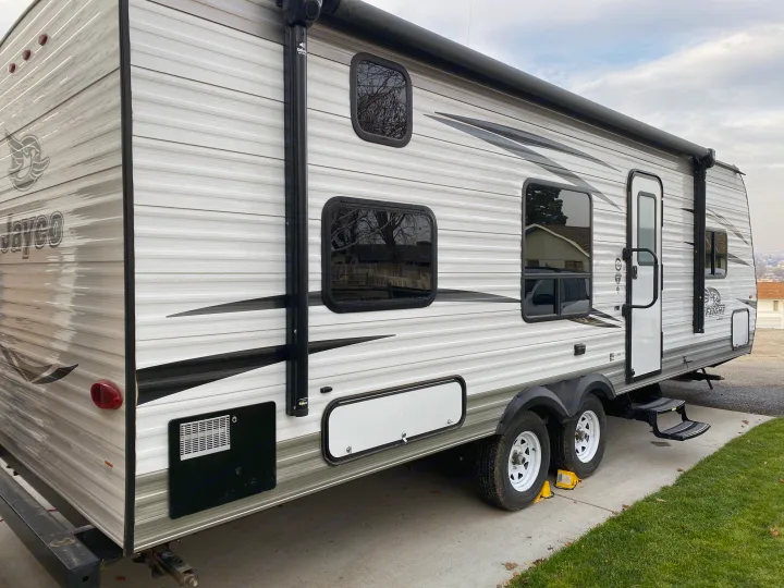 This RV rental is a modern travel trailer, ready for your next adventure. It's clean, grey/white, and parked on concrete.. Jayco Jay Flight 2018