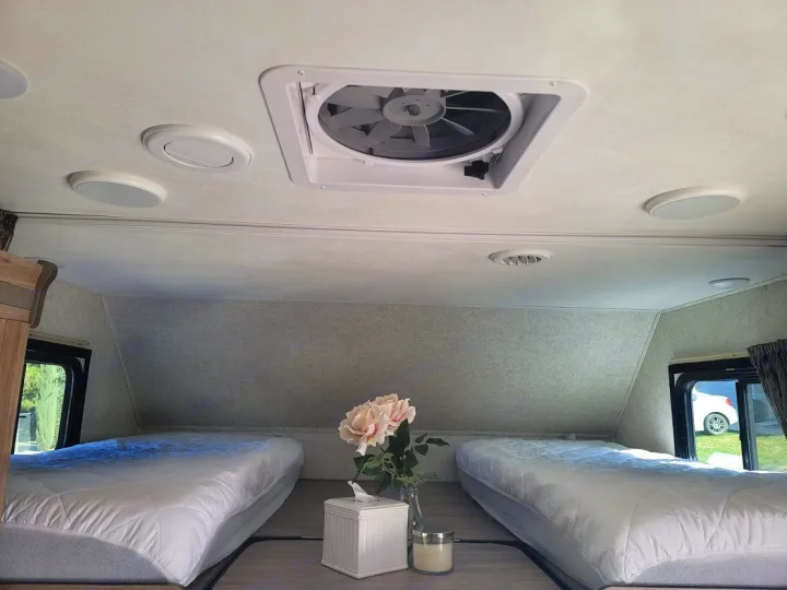 Comfortable RV rental interior with two beds, ceiling fan, and cozy decor. Ready for a relaxing trip.. Forest River Sunseeker 2019