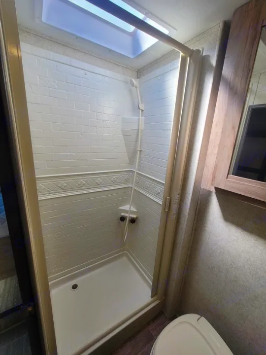 Step into this bright and clean shower with a skylight, a key feature in this RV rental's compact bathroom.. Forest River Sunseeker 2019