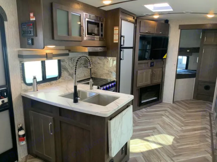 Bright rv rental interior: kitchen island, sink, microwave, fridge, TV, and bunk beds. Ready for your adventure.. Dutchmen Denali 2021