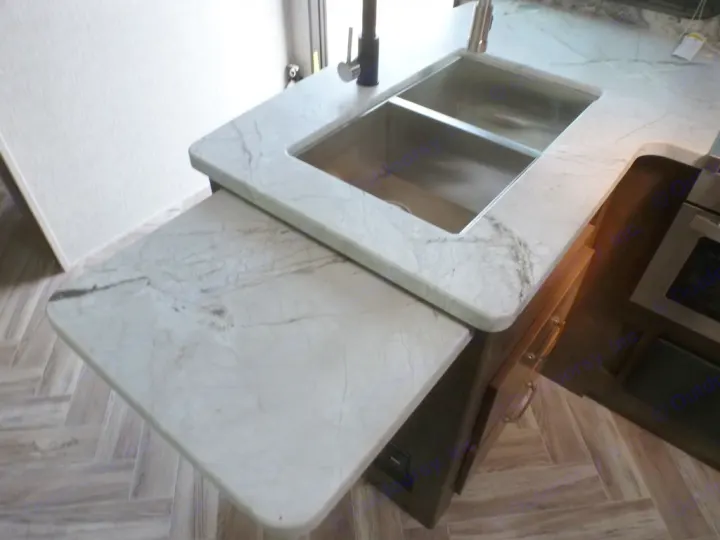 Modern rv rental kitchen featuring a marble-look counter, double sink, and a handy pull-out extension.. Dutchmen Denali 2021