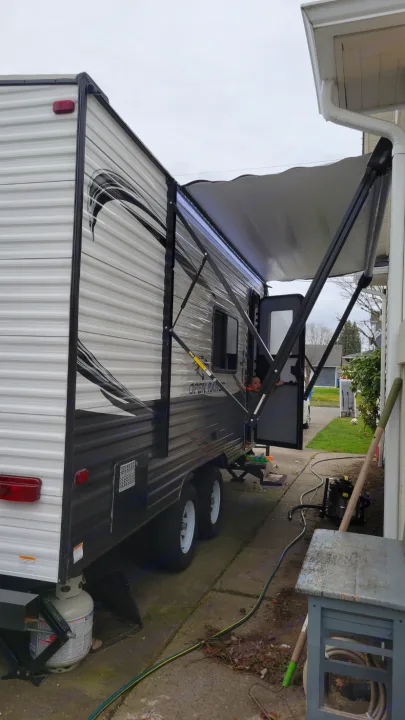 RV rental: Travel trailer with extended awning, a child visible inside the open door, parked on a narrow driveway.. Highland Ridge RV Open Range 2020