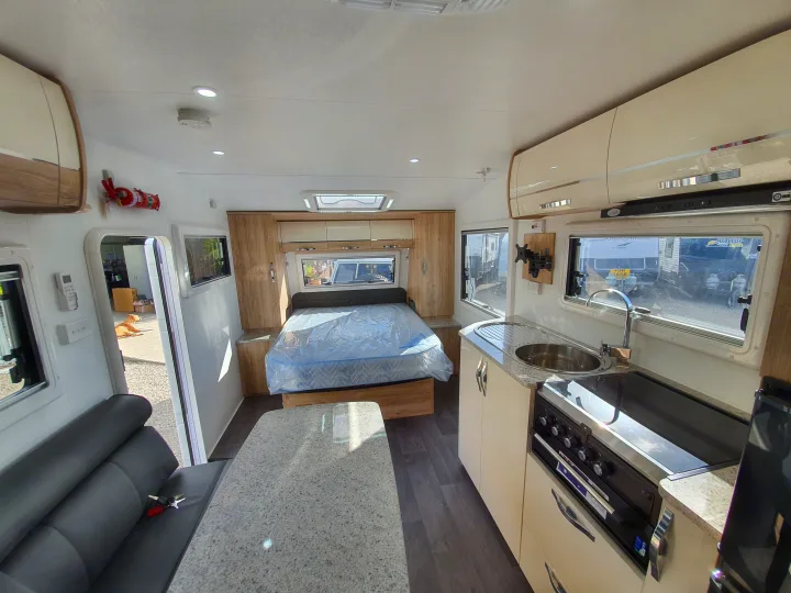 Bright rv rental interior showing a kitchen, dining area, and bedroom with bed. Ready for your mobile adventures!. Avan Aspire 555 2021