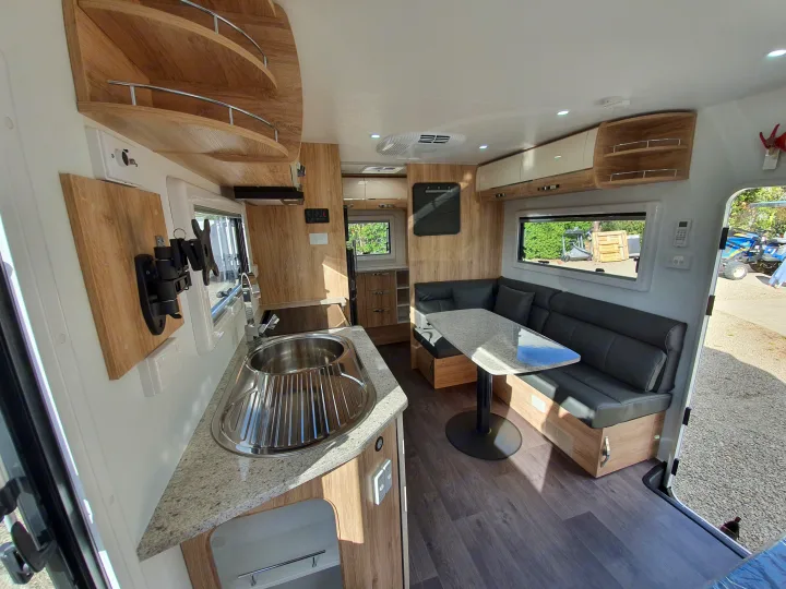 Modern RV rental interior featuring a full kitchen and U-shaped dining area with ample lighting.. Avan Aspire 555 2021