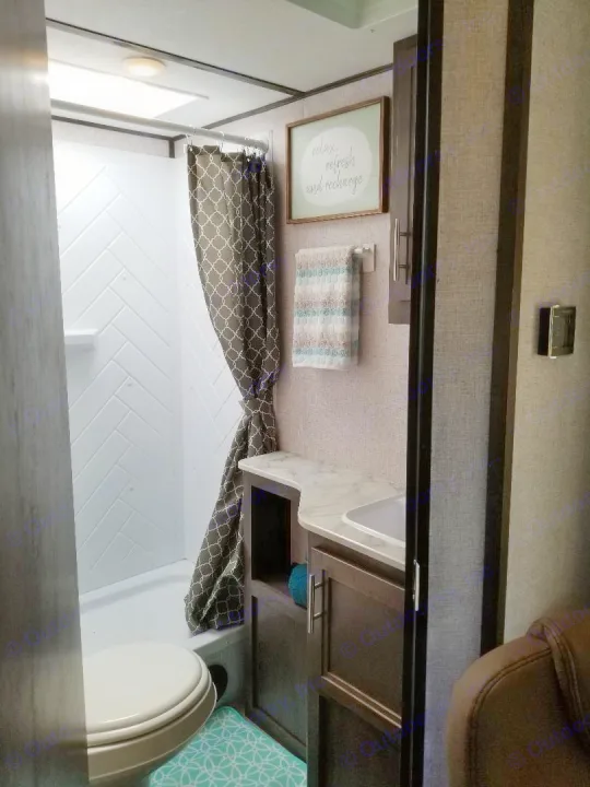 Compact and stylish RV rental bathroom featuring a shower, toilet, and vanity with modern finishes. Perfect for travel!. Dutchmen Coleman 2021
