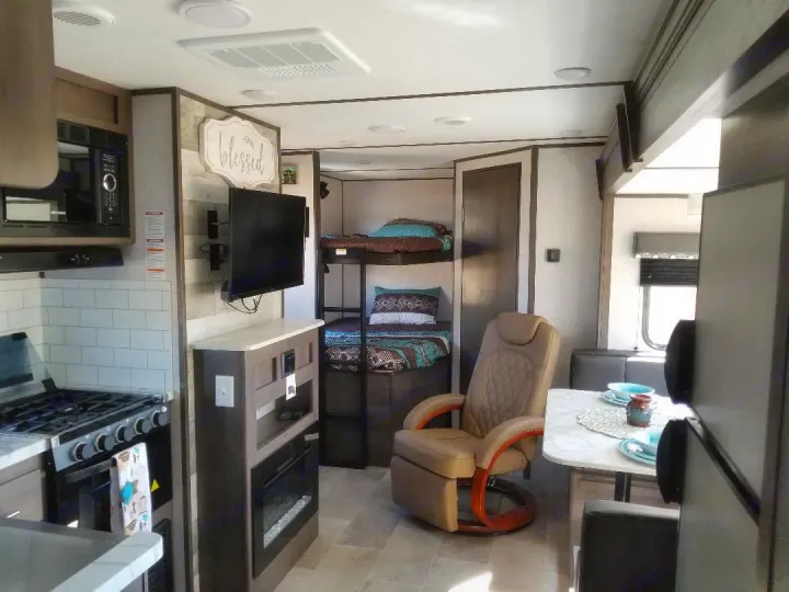 Cozy RV rental interior showcasing a modern kitchen, living area with TV/fireplace, bunk beds, and dining nook for comfort on the go.. Dutchmen Coleman 2021