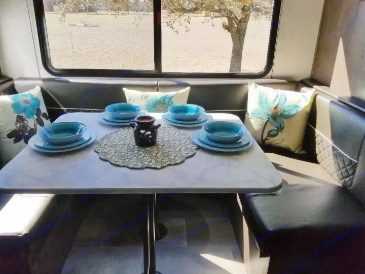 Cozy RV rental dining nook with a set table and floral pillows, ready for comfortable meals on your travels.. Dutchmen Coleman 2021