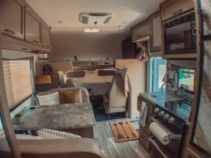 Step inside this RV rental, showcasing a modern kitchen and comfortable living area with a dinette.. Thor Four Winds 2021