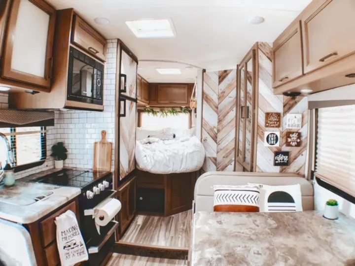 This RV rental boasts a renovated interior, featuring a modern kitchen, chevron walls, and cozy sleeping & dining areas.. Thor Four Winds 2021