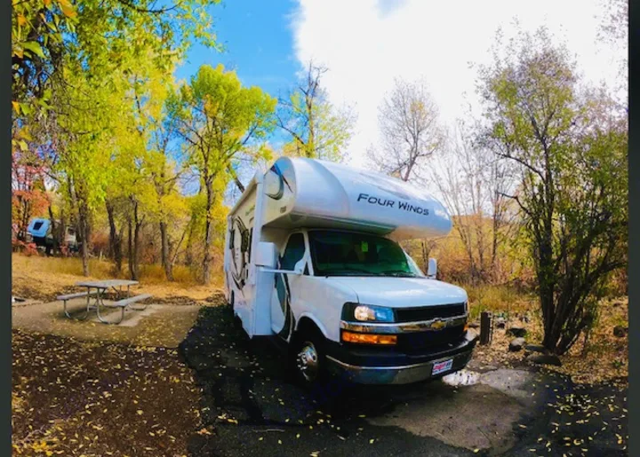 Autumn RV rental adventure! This Four Winds RV is perfectly parked at a scenic campsite with fall foliage.. Thor Four Winds 2021