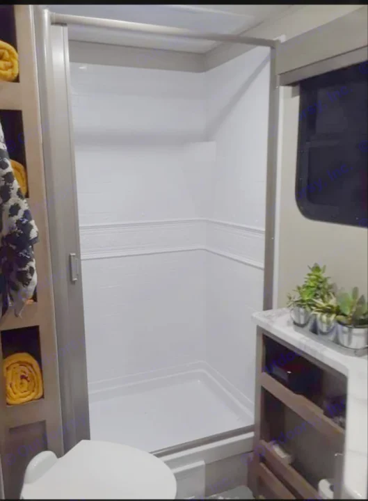 Compact RV rental bathroom with a bright white shower, toilet, and storage solutions. Ideal for road trips.. Grand Design Imagine 23 BHE 2021