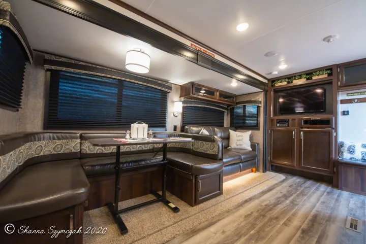 Modern RV rental interior features a cozy U-shaped dinette, sofa, and entertainment area, ideal for family trips.. Jayco Bunkhouse 2020