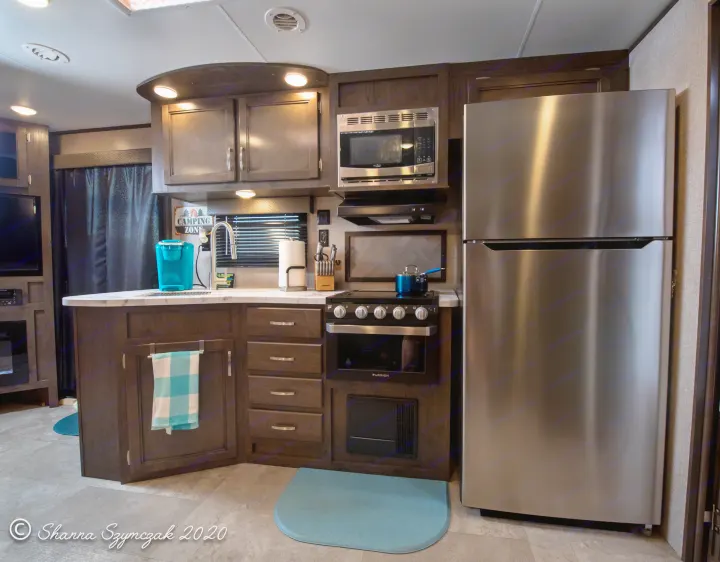 Well-equipped RV rental kitchen featuring a large refrigerator, microwave, stove/oven, and ample counter space.. Jayco Jay Flight 2020