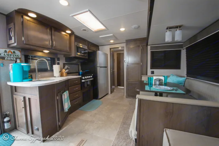 Modern RV rental interior featuring a full kitchen with dark wood cabinets, stainless appliances, and a cozy dinette.. Jayco Jay Flight 2020