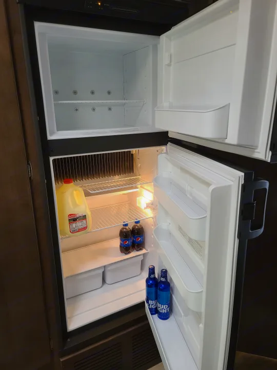 An open RV rental fridge/freezer, stocked with Pepsi, Bud Light, and milk, ready for your next adventure.. Thor Freedom Elite 2019