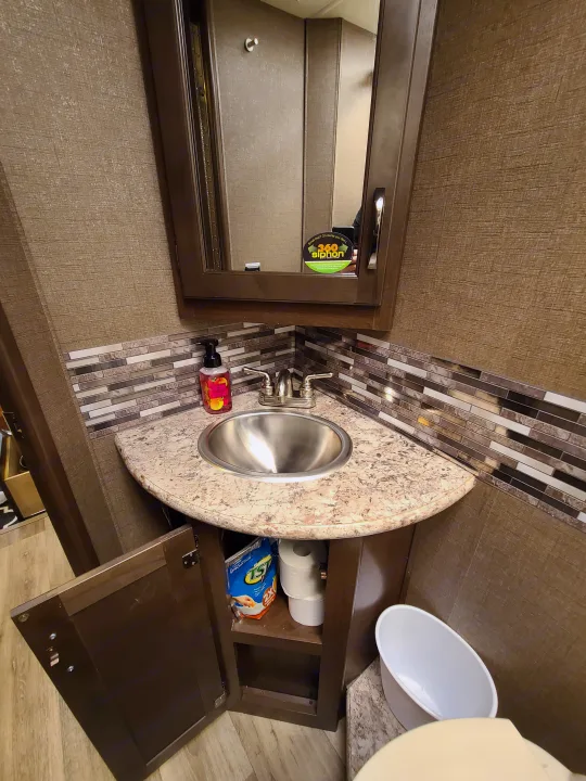 RV rental bathroom: compact vanity with sink, stylish backsplash, mirror, and essentials storage.. Thor Freedom Elite 2019