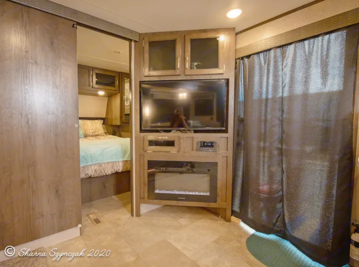 Inside a modern rv rental: living area with built-in TV, fireplace, and sliding door to bedroom. Cozy and functional.. Jayco Jay Flight 2020