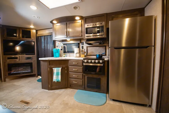 Step inside this modern RV rental's full kitchen and living space. Features stainless steel appliances, cabinets, and a TV.. Jayco Jay Flight 2020