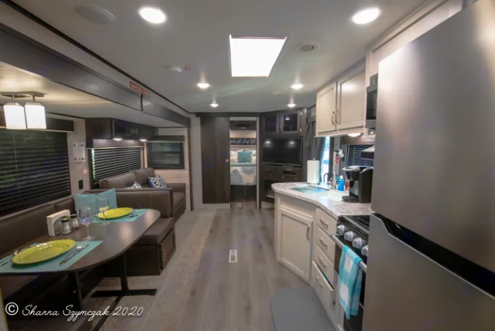 Inside a modern RV rental: well-appointed kitchen, dining booth, and living room with a peek into the bedroom.. Jayco Jay Flight 2021