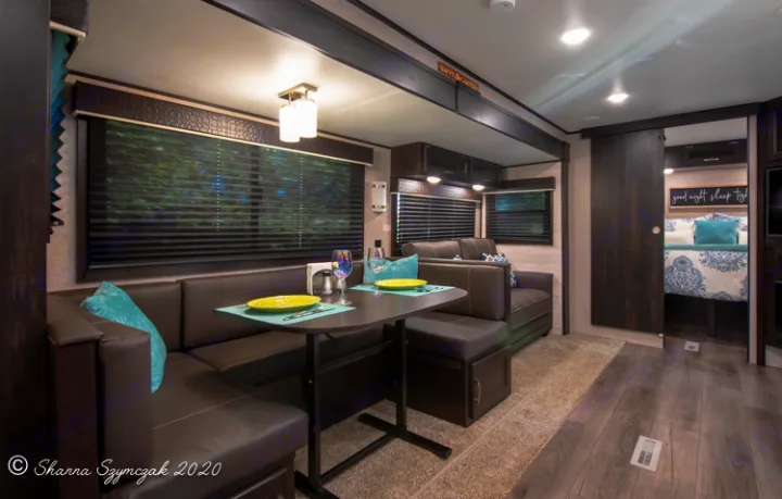 Cozy RV rental interior shows dining booth, lounge area, and a glimpse of the bedroom beyond a sliding door.. Jayco Jay Flight 2021