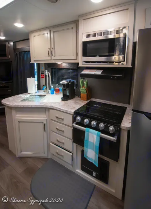 Modern RV rental kitchen: sink, microwave, stove, coffee maker, & light cabinetry. Ready for your travels!. Jayco Jay Flight 2021