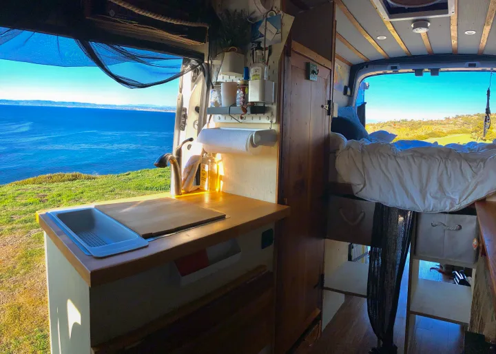 Experience van life in this rv rental! Cozy interior with kitchen, bed, and stunning ocean views protected by a mosquito net.. Ford Transit 2017