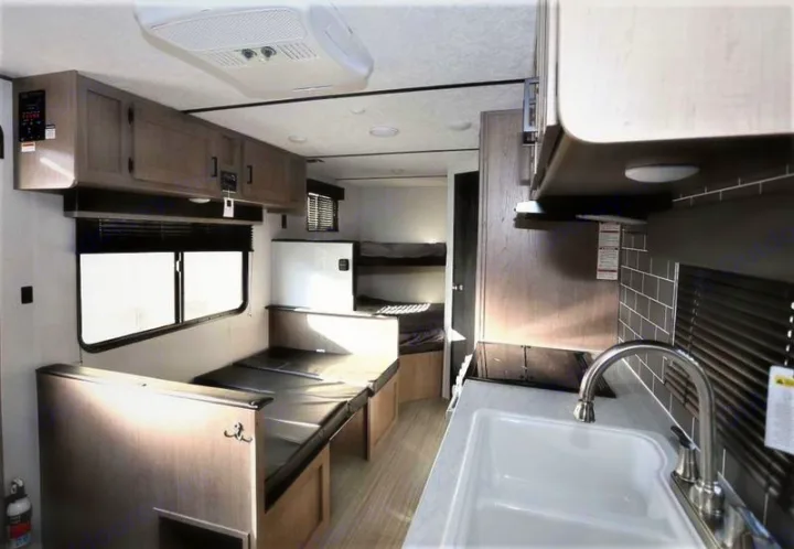 Compact RV rental interior featuring a kitchen area, convertible dinette, and bunk beds for efficient living.. Keystone Hideout 2021