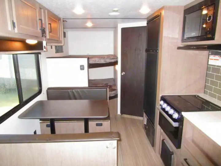 Modern rv rental interior featuring a kitchen, dinette, and bunk beds, offering a compact living space.. Keystone Hideout 2021