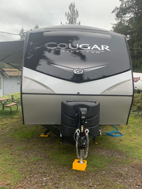 This Cougar Half-Ton travel trailer, ideal for an RV rental, is set up at a scenic campsite.. Keystone Cougar Half-Ton 2021