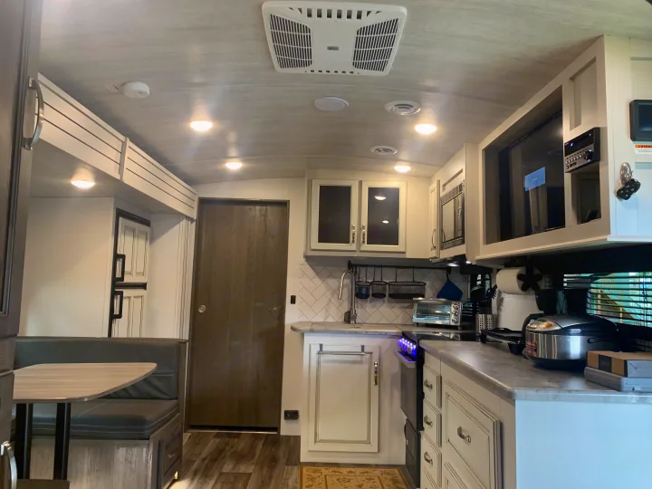 Modern RV rental interior with kitchen, dinette seating, and essential amenities for comfortable travel.. Keystone Cougar Half-Ton 2021