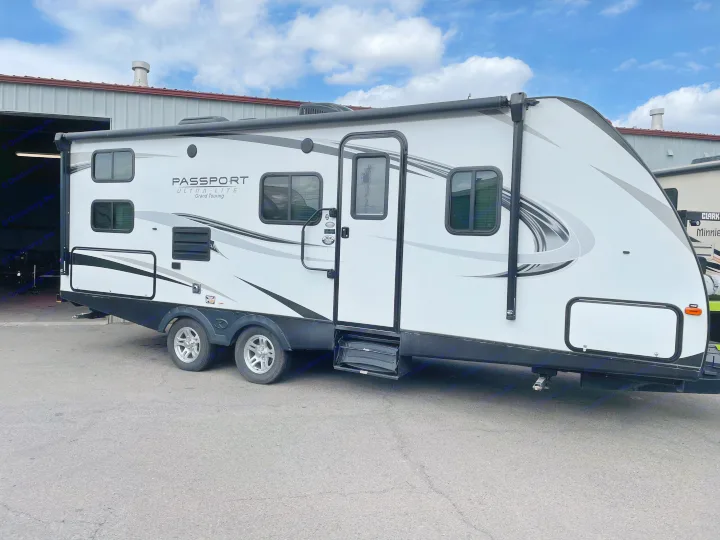 White Passport Ultra-Lite travel trailer parked outdoors, ideal for your next RV rental adventure.. Keystone Passport 2400BHWE 2018