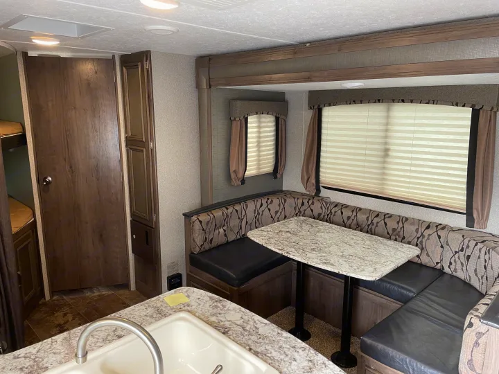 Spacious RV rental interior featuring a comfortable dinette, kitchen area, and bunk beds.. Keystone Passport 2400BHWE 2018