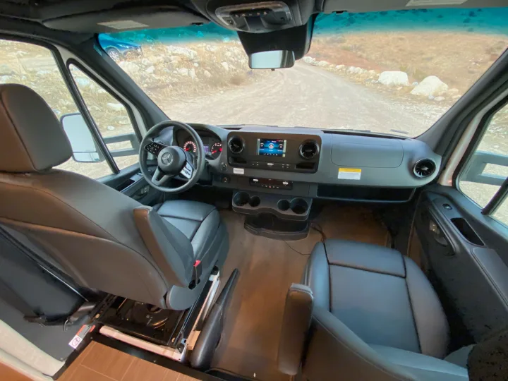 Spacious RV rental cockpit features a modern dashboard, steering wheel, touchscreen display, and comfortable front seats.. Winnebago Vita 2020