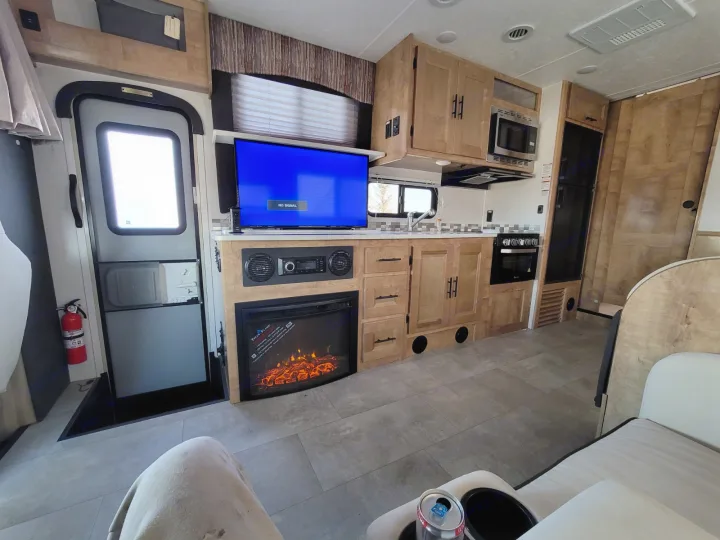 Modern RV rental interior: fully equipped kitchen, entertainment TV/fireplace, and comfortable living space for your adventures.. Coachmen Leprechaun 2021